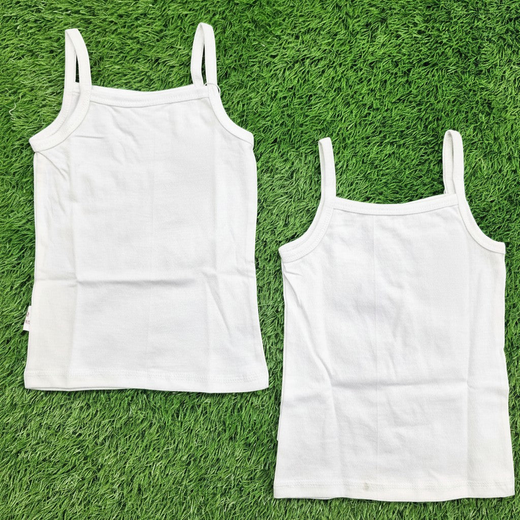 3. white cotton camisole slips with thin spaghetti straps, laid flat on a green grass background.
