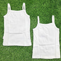 3. white cotton camisole slips with thin spaghetti straps, laid flat on a green grass background.
