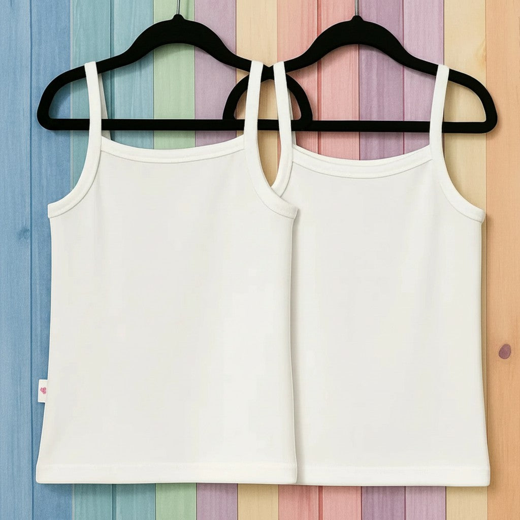 3. white cotton camisole slips with thin spaghetti straps hanging on black hangers against a colorful wooden background